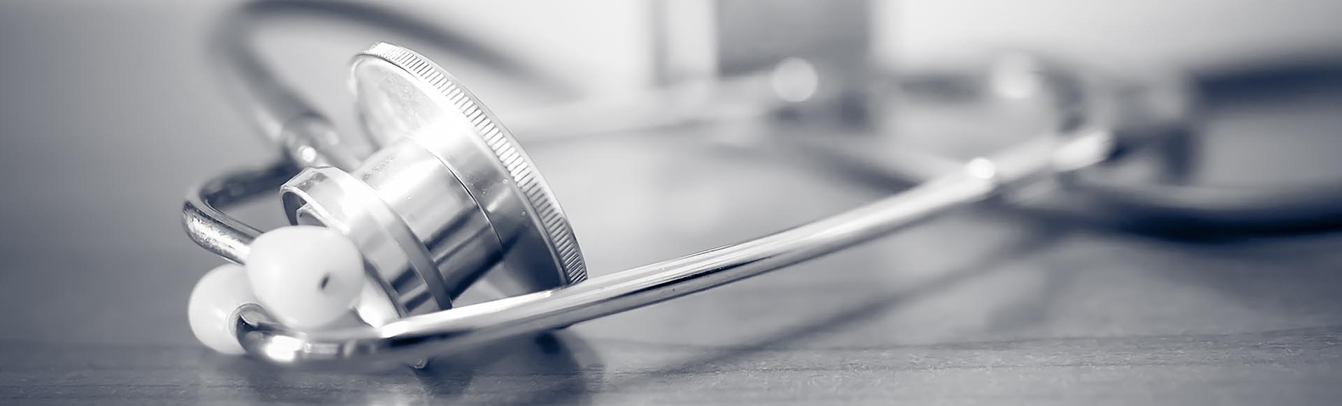 stethoscope on table with vaccine bottle behind